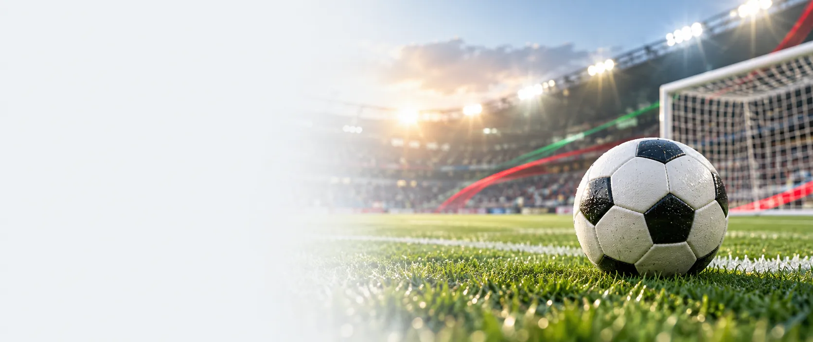 Pelota de fútbol sobre el césped frente al arco de un estadio